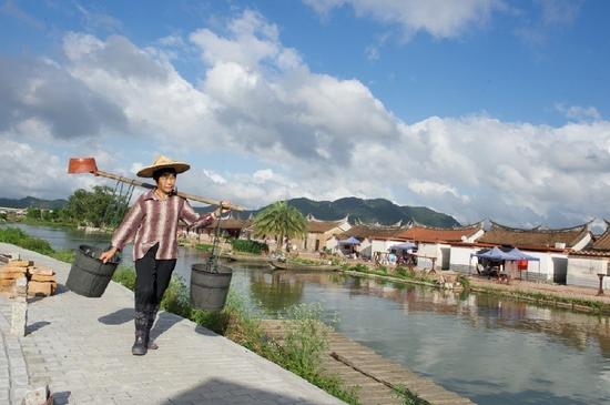 5月27日，埭美村一位村民挑桶經(jīng)過(guò)村前小河