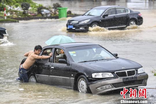 6月13日，惠州惠東縣新平大道上，市民在雨中推行拋錨的車輛?！￡愺K旻 攝