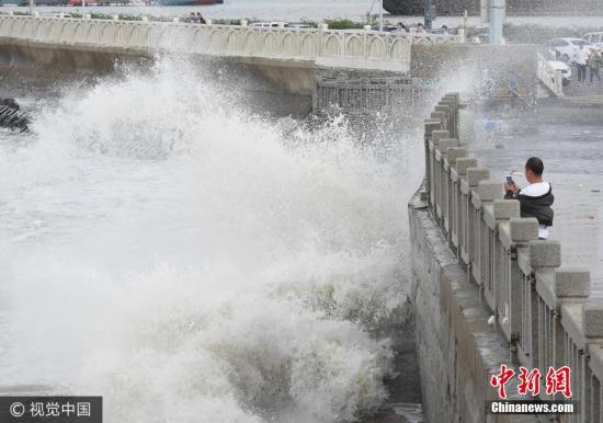 10月2日，游客在連云港市連云區(qū)海岸邊觀賞巨浪。當日，受冷空氣影響，江蘇連云港沿海出現(xiàn)大風，海濱掀起陣陣巨浪。據(jù)中央氣象臺預報，10月1日夜間至4日，冷空氣將自北向南影響我國中東部大部地區(qū)，長江中下游及其以北地區(qū)有4-5級風，陣風6-7級，日平均氣溫或最低氣溫將下降4-6℃，北方部分地區(qū)降溫幅度可達10℃以上。耿玉和 攝 圖片來源：視覺中國