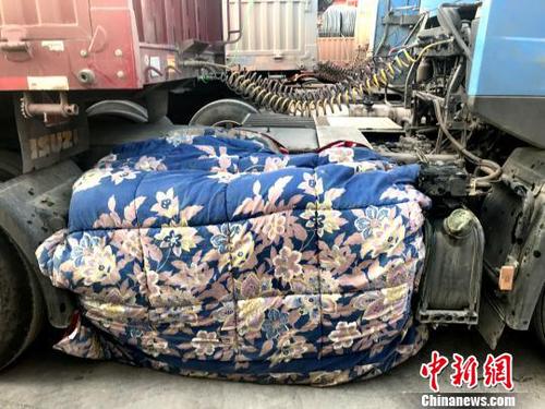 圖為卡車司機(jī)用棉被為卡車“取暖”?！＄娦?攝