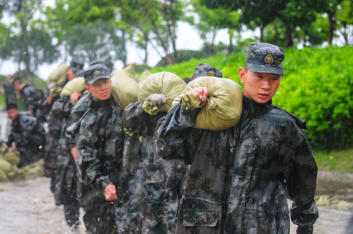 圖為在安徽合肥巢湖任務(wù)區(qū)官兵在暴雨中扛運(yùn)沙袋，加固堤壩。（王文洲 攝）